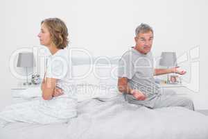Couple sitting on different sides of bed having a dispute
