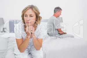 Unhappy couple sitting on different sides of bed having a disput