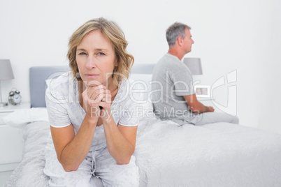 Thoughtful couple sitting on different sides of bed having a dis
