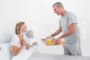 Loving husband bringing breakfast in bed to wife