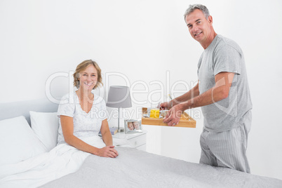 Happy husband bringing breakfast in bed to wife