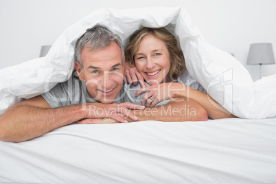 Cheerful couple under the duvet