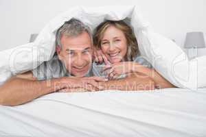 Cheerful couple under the duvet