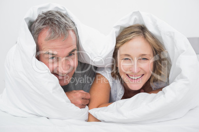 Happy middle aged couple under the duvet