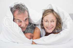 Happy middle aged couple under the duvet
