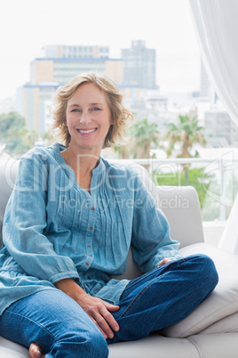 Happy blonde woman sitting on her couch