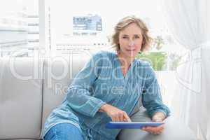 Blonde woman relaxing on her couch using her tablet