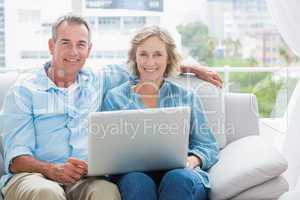 Happy couple relaxing on their couch using the laptop