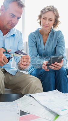 Wife watching her husband cut credit card in half