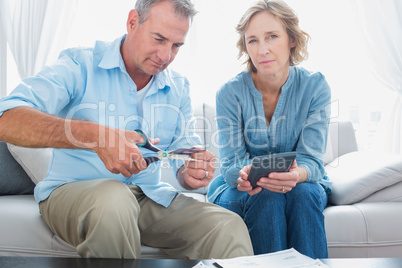 Husband cutting credit card in half with wife looking at camera