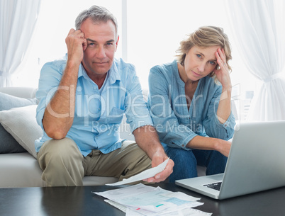 Anxious couple paying their bills online with laptop