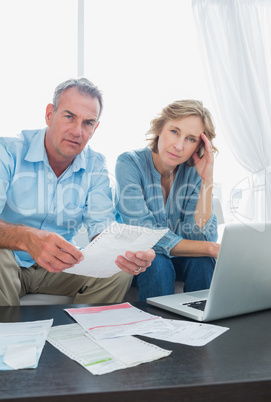 Anxious couple paying their bills online with laptop looking at