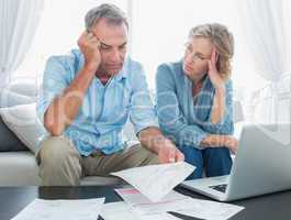 Worried couple using their laptop to pay their bills