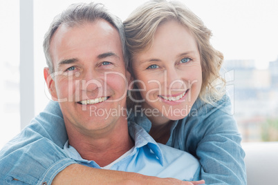 Smiling woman hugging her husband on the couch from behind