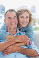 Happy woman hugging her husband on the couch from behind