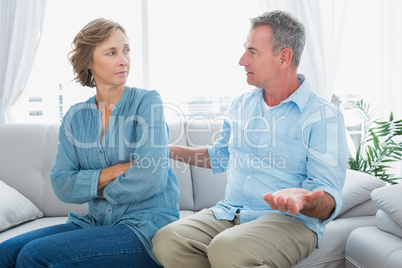 Middle aged couple sitting on the sofa having a dispute