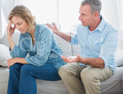 Middle aged couple sitting on the couch having a dispute