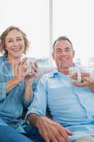 Happy middle aged couple sitting on the couch having coffee