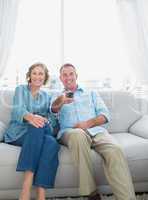 Smiling middle aged couple sitting on the couch watching tv