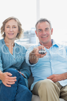 Cheerful middle aged couple sitting on the couch watching tv