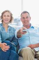 Cheerful middle aged couple sitting on the couch watching tv