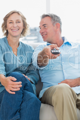 Cheerful couple sitting on the couch watching tv