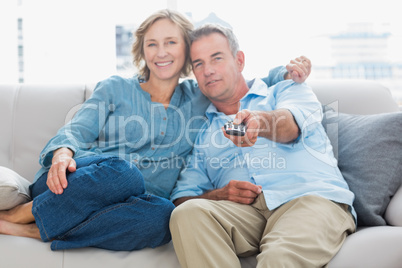 Happy couple cuddling and sitting on the couch watching tv