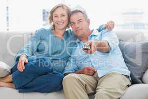 Happy couple cuddling and sitting on the couch watching tv