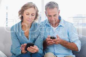 Smiling couple using their smartphones