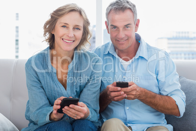 Happy couple using their smartphones