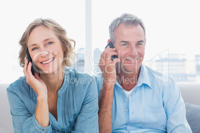 Happy couple on their mobile phones on the couch