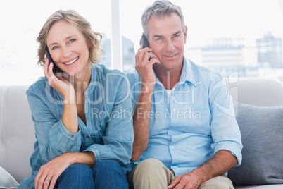 Cheerful couple on their mobile phones on the couch