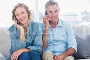 Cheerful couple on their mobile phones on the couch