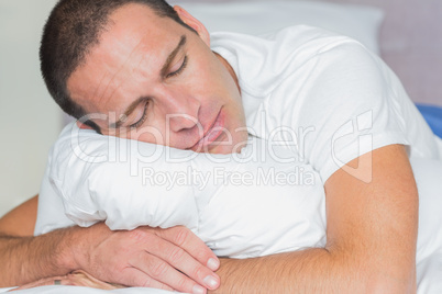 Sleeping man hugging his pillow