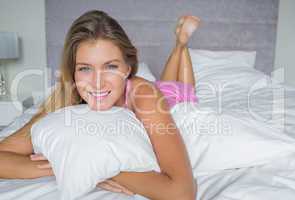 Happy blonde lying on her bed smiling