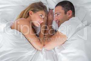 Cute couple lying and looking at each other in bed