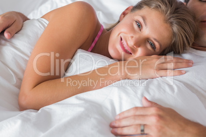 Smiling woman lying on husbands chest in bed