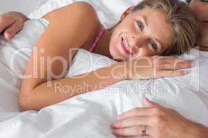 Smiling woman lying on husbands chest in bed