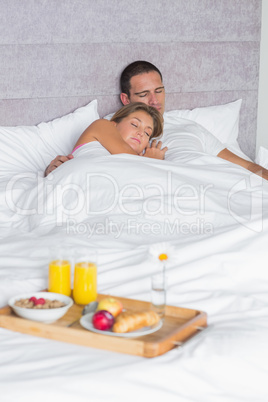Couple asleep with breakfast tray on bed