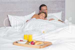 Attractive couple sleeping with breakfast tray on bed