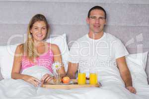 Attractive couple having breakfast in bed