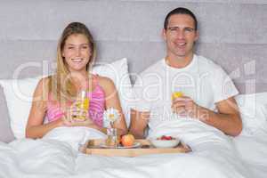 Happy young couple having breakfast in bed