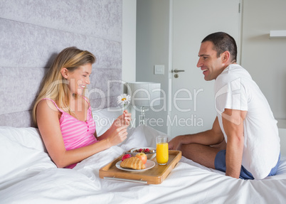 Happy woman being brought breakfast in bed by husband