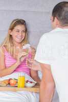 Pretty woman taking a daisy from partner at breakfast in bed