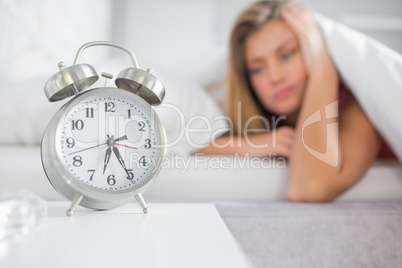 Tired blonde staring at her alarm clock