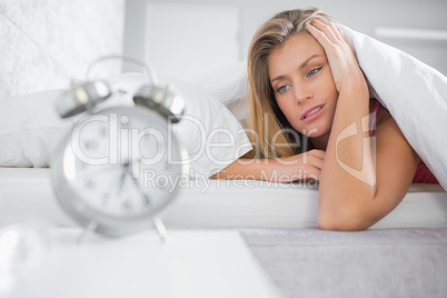 Exhausted blonde staring at her alarm clock