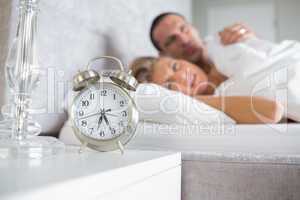 Exhausted couple looking at alarm clock