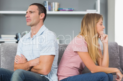 Couple sitting back to back after a fight on the couch