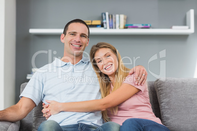 Couple sitting on the couch smiling at camera