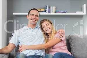 Couple sitting on the couch smiling at camera